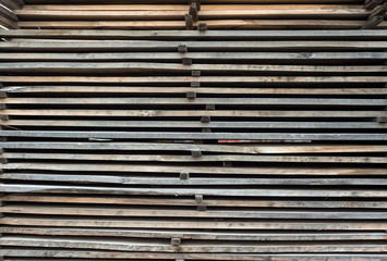 Folded wooden brown and gray planks in a sawmill. Piled alder boards as texture.