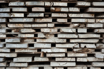 Folded wooden brown and gray planks in a sawmill. Piled alder boards as texture.