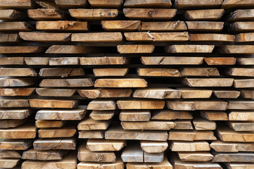 Folded wooden brown and gray planks in a sawmill. Piled alder boards as texture.