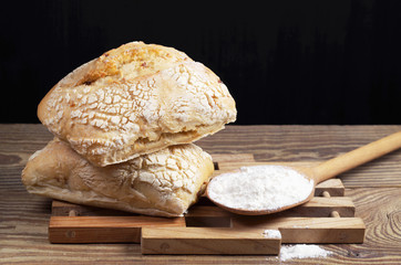 Two loaves of ciabatta bread and a spoon with flour