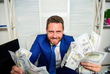 Earn money easy business tips. Man cheerful happy businessman with pile dollar banknotes. Profit and richness concept. Cheсk out my profit this month. Businessman formal suit hold cash dollars hands