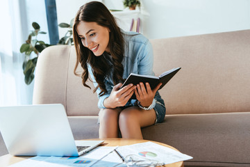 smiling young businesswoman with notebook remote working at home