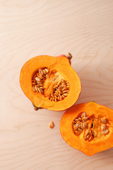 Two halves of raw pumpkin with seeds on wooden background