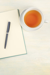 An overhead photo of an open journal with a pen and a cup of tea, shot from above with copy space