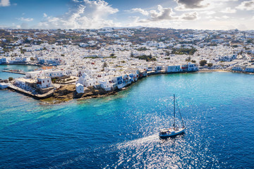 Die Bucht von Mykonos Stadt in Griechenland mit tiefblauem Meer und vorbeifahrendem Segelboot;...