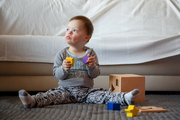 Portrait of cute boy with Down syndrome playing in home living room