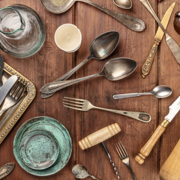 An overhead photo of many vintage kitchen objects and cutlery from an old restaurant, flea market stuff on a wooden background