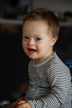 Portrait of cute small boy with Down syndrome in home living room