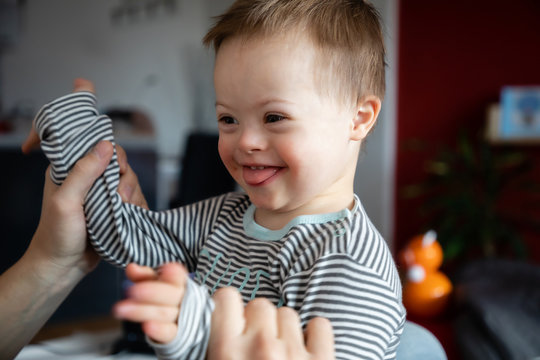 Cute boy with Down syndrome playing with dad on in home living room