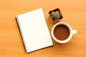 Obraz na płótnie Canvas Top view of blank notebook with cactus and hot coffee on wood table on white wall background,flay lay.
