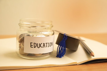 Graduation hat with glass jar saving money scholarship for education in future on wood table,vintage.