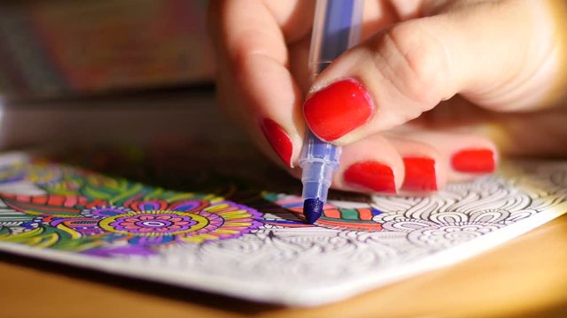 Painting adult coloring book at evening home by reading-lamp light