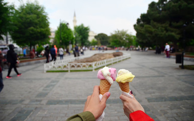Two female hands holding turkish ice cream Dondurma in Sultanahmet Squarea, Istanbul.  Dondurma - is a Turkish mastic ice cream. Focus on hands. 