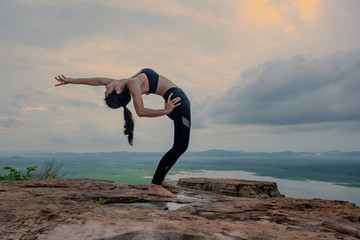 woman practice yoga training on the top peak of mountain, river and lake in background.