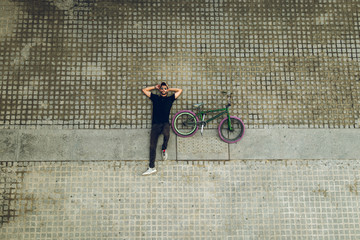 Guy looking at the camera with a bmx bike on the street. Guy with a bmx for the city