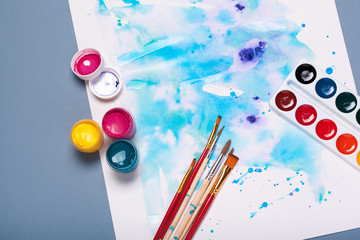 Top view of work process of watercolor paper pad, watercolor painting supplies and brushes