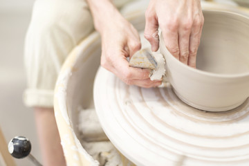 Woman hands makes clay pot on the pottery wheel