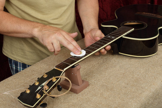 Guitar repair and service - Worker moistening and impregnation of an fingerboard neck black guitar special oil