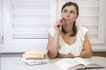 A young girl doing homework. Studying at the University. Woman in the process of learning. Student with books.