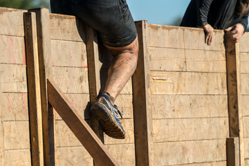 Athlete climbing over a wooden wall at an obstacle course race 