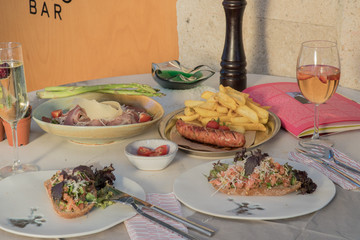 Appetizing big grilled sausage with homemade fried potatoes at the dinner restaurant with fresh vegetables.