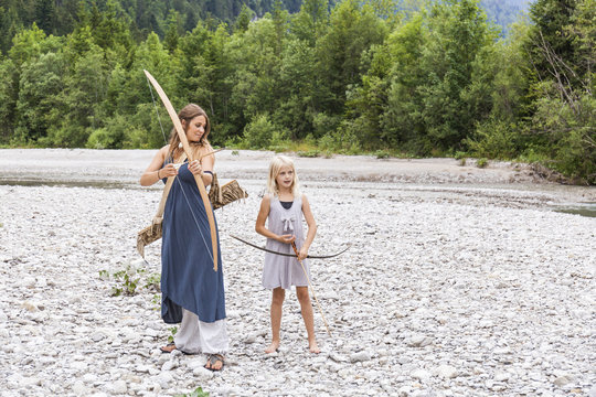 Mother and daughter with bow and arrow in the nature