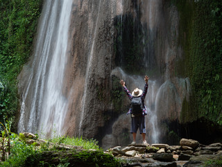 Senior man with backpacks enjoying waterfall raised hands Travel Lifestyle and success concept