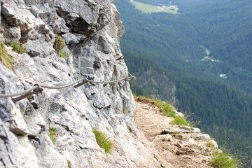 On an excursion trail on the italian mountains, the Dolomites, a part of the Alps range. Here a narrow spot on the way that faces a huge valley and a nice landscape