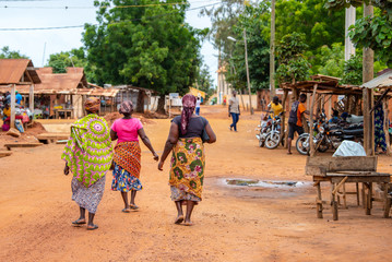 Togoville village in Togo. Women walking in African outfits in the village. Voodoo religion in Togo, West Africa. Togoville and Lomé voodoo markets. - obrazy, fototapety, plakaty