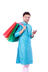 Indian man in ethnic wear with shopping bags and showing mobile screen , isolated over white background