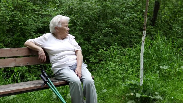 old granny sits resting on a park bench