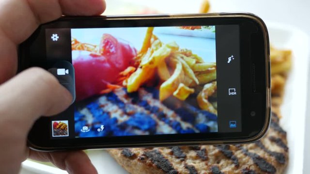 Closeup taking a photo picture of food via his smartphone camera