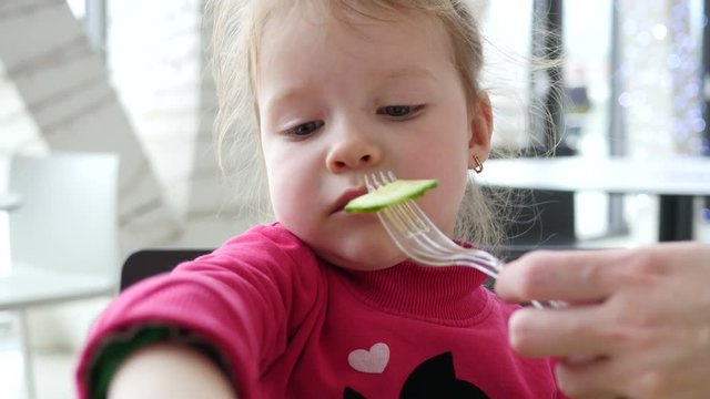 Cute little child girl eating vegetables instead of meat in fast food cort