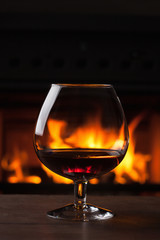 glass of cognac in front of fireplace