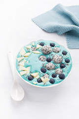 Obraz na płótnie Canvas healthy blue spirulina smoothie bowl with blueberry, white chocolate, dragon fruit, chia seed