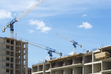 High construction cranes on a construction site with workers