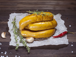 Raw curry sausages on crumpled paper on wooden table