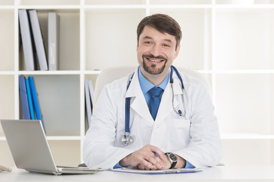 Male doctor working at office desk
