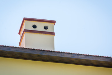 House square tube comes out of roof against blue sky background.