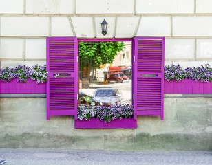 Cafe window with violet shutters and flowers on the windowsill