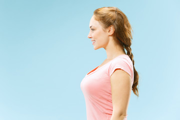 Happy business woman standing and smiling isolated on blue studio background. Beautiful female half-length portrait. Young emotional woman. The human emotions, facial expression concept.