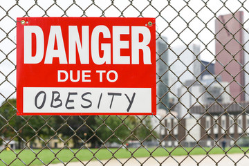  Sign danger due to obesity hanging on the fence