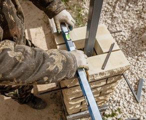 The worker is laying bricks on the fence