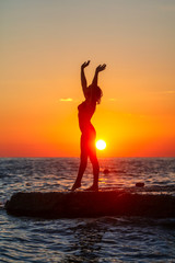 Fototapeta na wymiar Silhouette of a girl at sunset on the sea