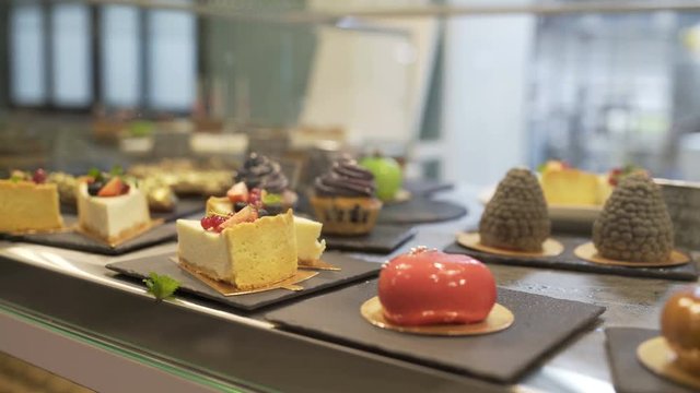 Window of cake shop with variety of cakes on display. Pastry shop with of muffins, eclaire, cakes with fruits, berries