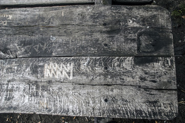 napisy wydrapane lub wypalone na starej drewnianej ławie parkowej 