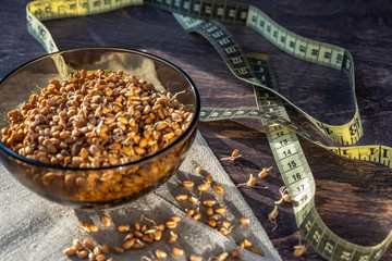 Wheat germ seeds and measuring tape on wooden background.
