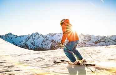 Professional skier athlete skiing at sunset on top of french alps ski resort - Winter vacation and sport concept with adventure guy on mountain top riding down the slope - Warm bright sunshine filter - obrazy, fototapety, plakaty