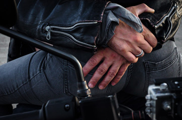 hands of a biker man hugging a biker woman's back sitting on a motorcycle