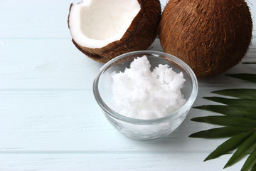 coconuts and coconut oil with tropical leaves on a wooden background